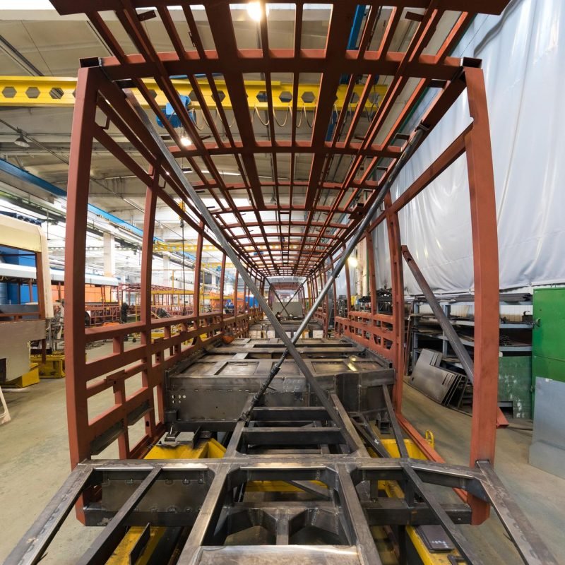 one-working-day-modern-automatic-bus-trolleybus-car-production-with-unfinished-cars-workers-protective-uniform-automotive-background-automobile-assembly-line-welding-arm